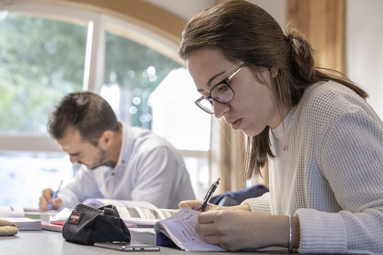 Two students writing in their Dutch workbooks